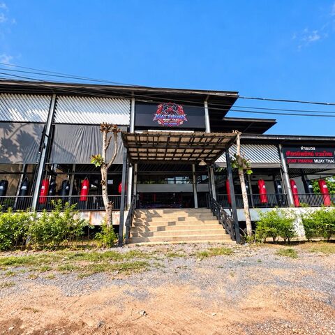 The Kiat Phayak Muay Thai building: an open-air gym with heavy bags along the front and the tiger logo on the roof