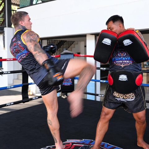A student throws a roundhouse kick on the pads